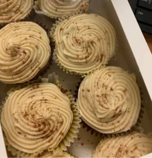 A box of cupcakes with frosting on top.