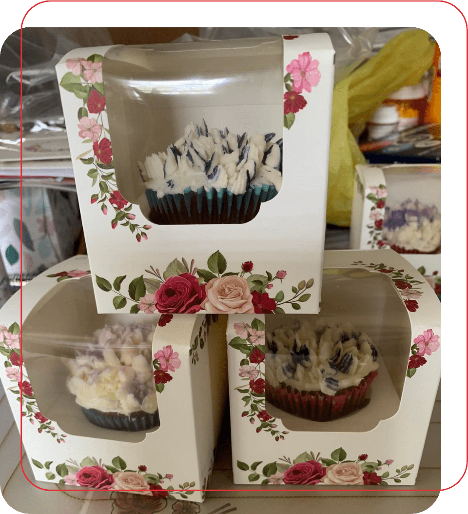 Three cupcakes in a box with flowers on them.