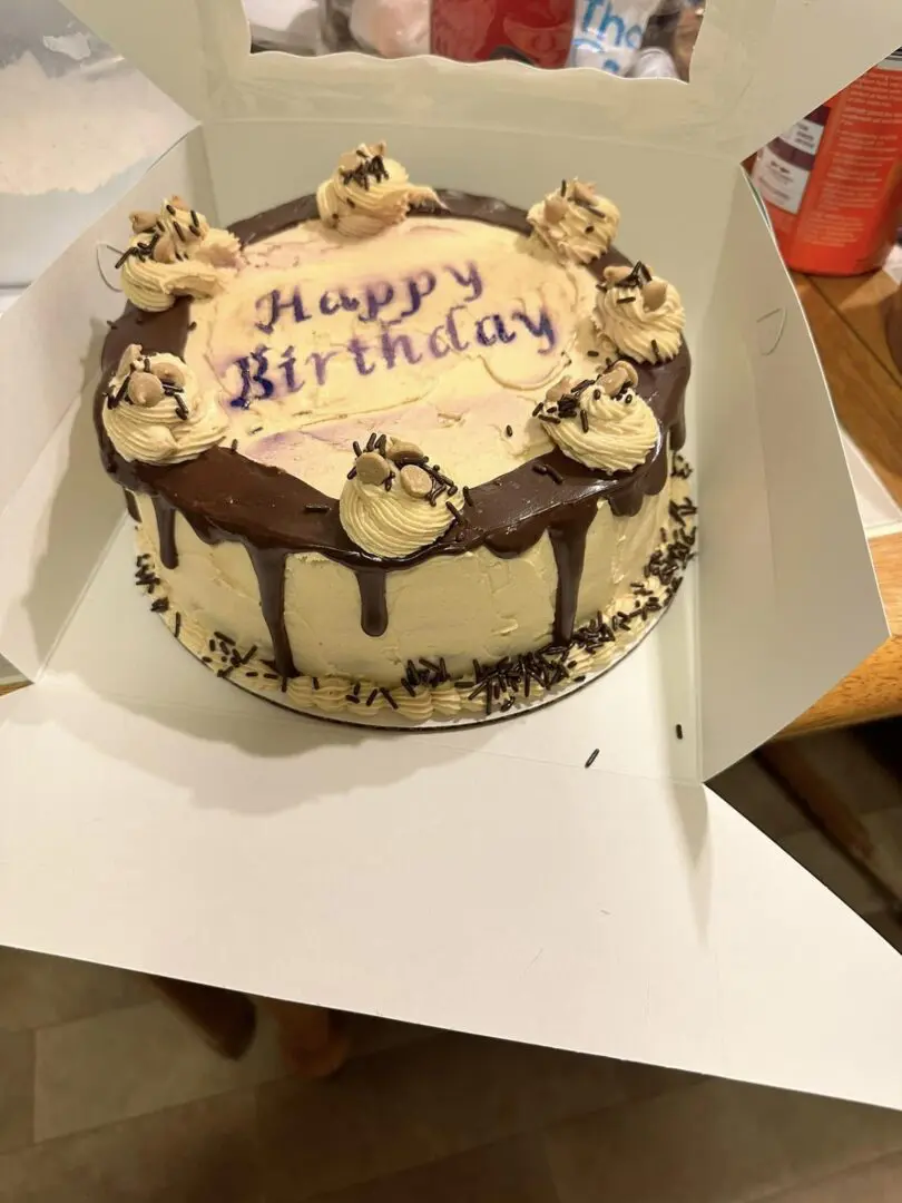 A birthday cake with chocolate frosting and white icing.