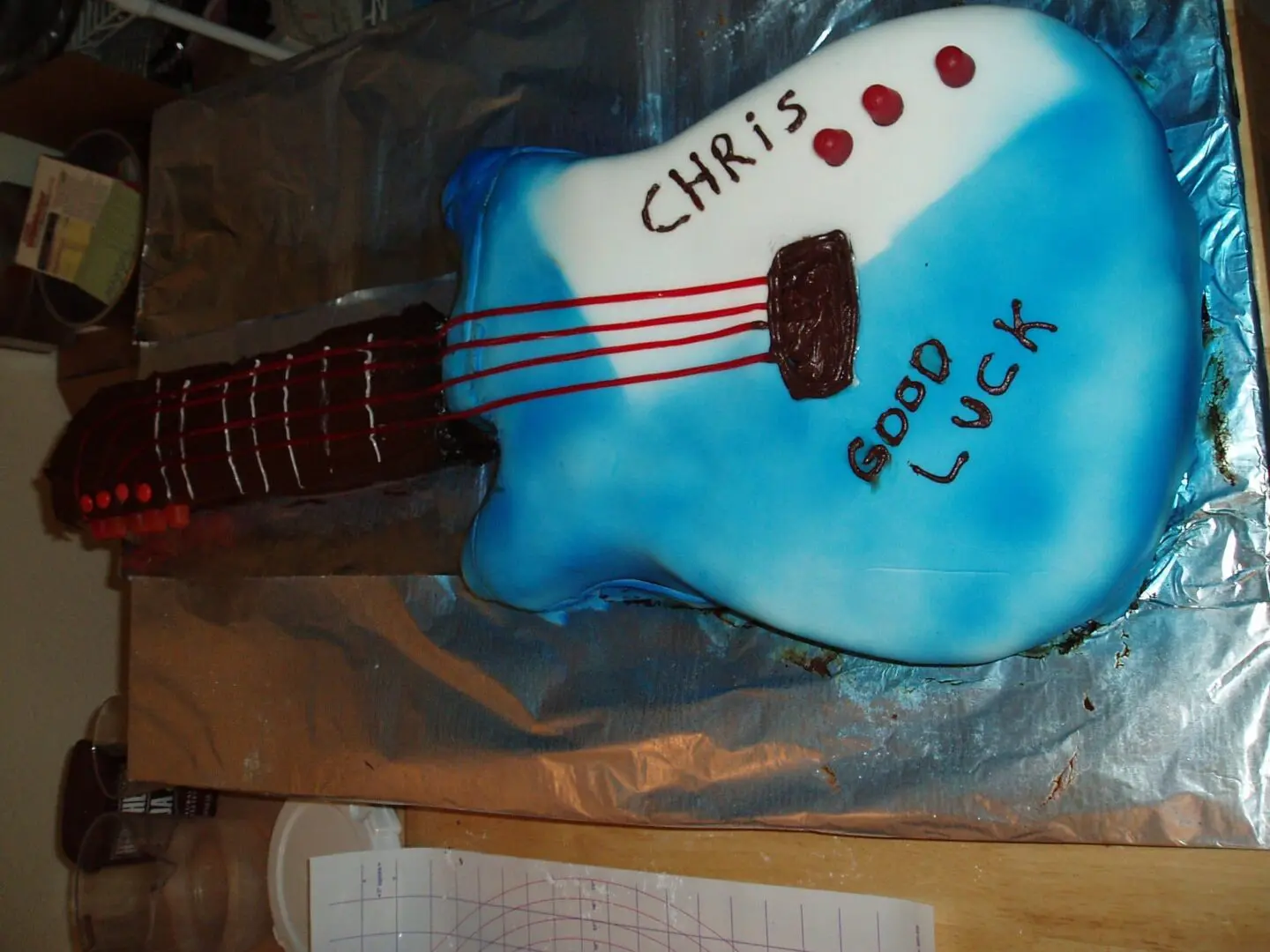 A blue guitar cake with the name of chris on it.